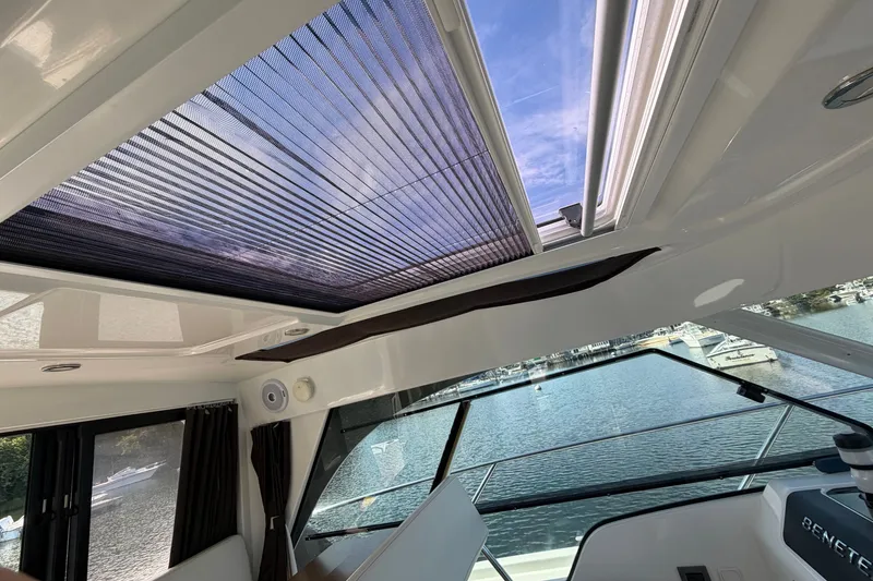 Slide: The Image of Interior view of 2021 Beneteau Antares 27 with open sunroof and scenic water backdrop. - 17