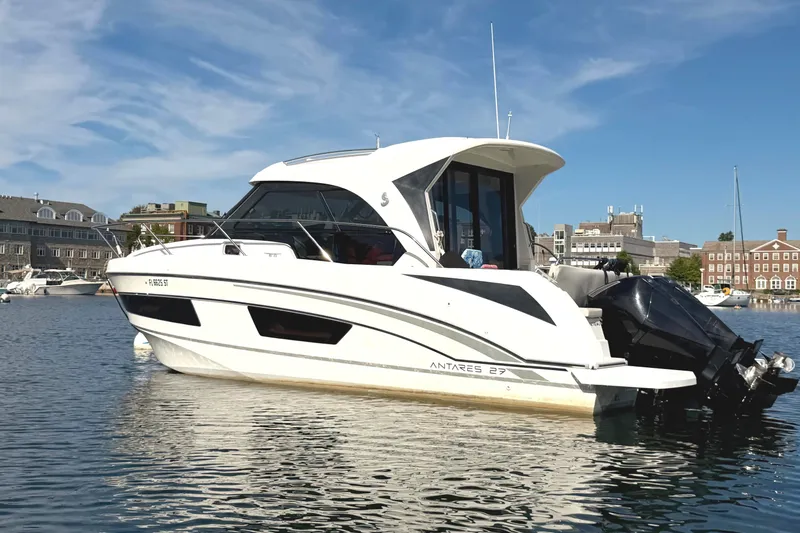 Slide: The Image of 2021 Beneteau Antares 27 boat on calm water, cityscape background. - 2