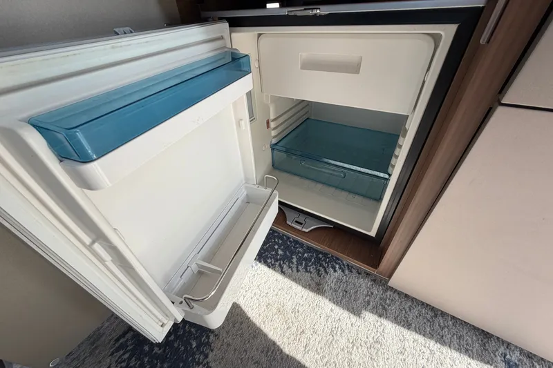 Slide: The Image of Open refrigerator inside 2021 Beneteau Antares 27 boat, showcasing interior storage space. - 27