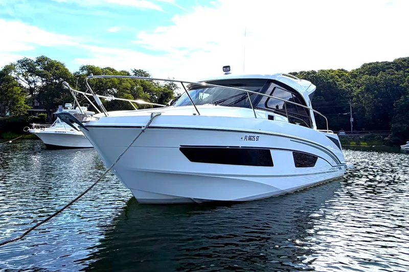 Slide: The Image of 2021 Beneteau Antares 27 boat anchored on calm water, surrounded by trees. - 5