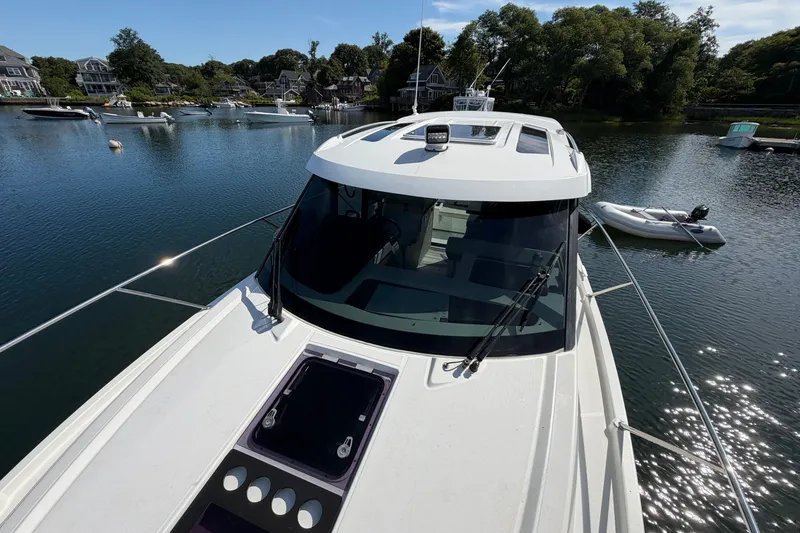 Slide: The Image of 2021 Beneteau Antares 27 boat docked in a serene marina with lush greenery. - 35
