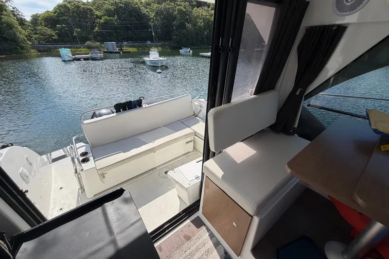 Slide: The Image of Interior view of 2021 Beneteau Antares 27 boat with seating and water backdrop. - 13