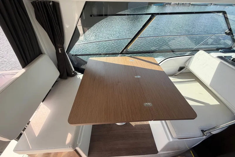 Slide: The Image of Interior of 2021 Beneteau Antares 27 with wooden table and seating, overlooking water. - 18