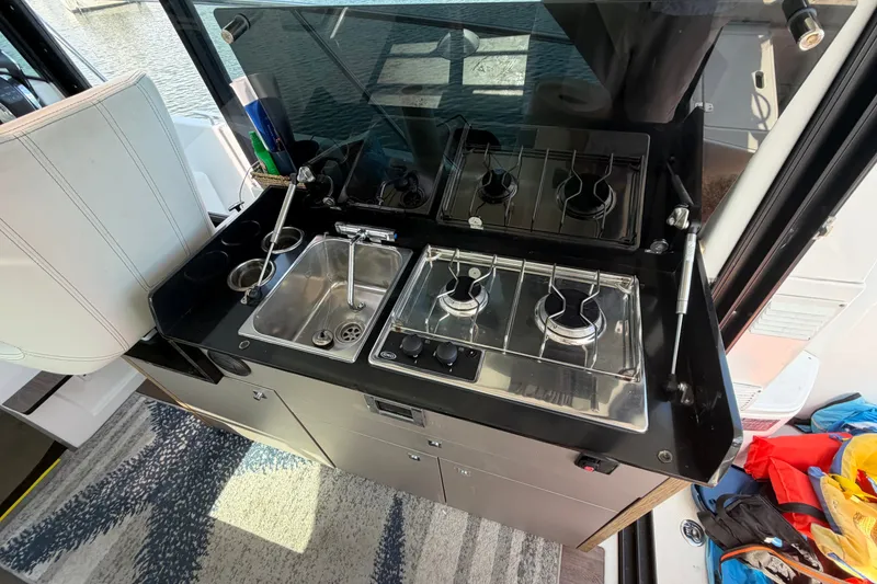 Slide: The Image of Compact kitchen area on a 2021 Beneteau Antares 27 boat, featuring a stove and sink. - 26