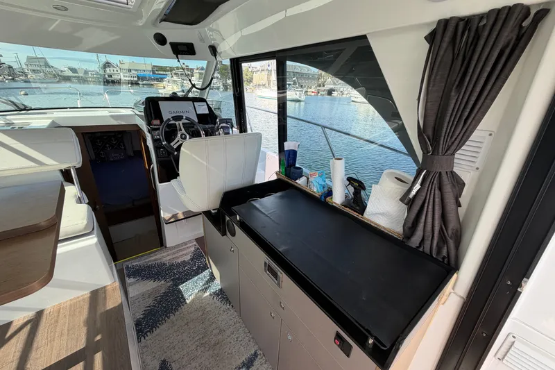 Slide: The Image of Interior of 2021 Beneteau Antares 27 boat with helm, seating, and waterfront view. - 11