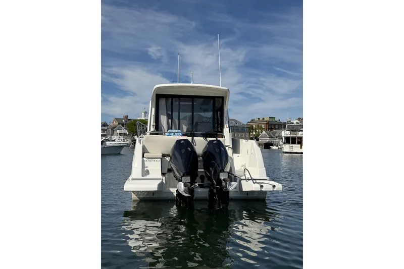Slide: The Image of 2021 Beneteau Antares 27 boat docked in a marina, rear view with dual engines. - 44