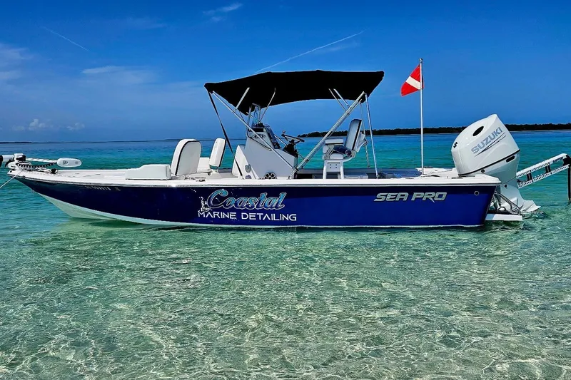 The Image of A blue 2021 Sea Pro 228 Bay boat with a black sunshade, floating on clear water. - 0