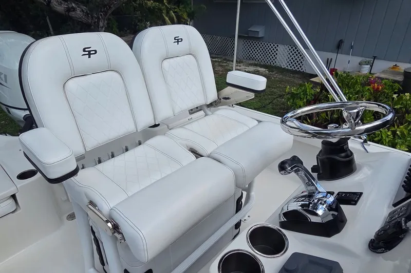 Slide: The Image of 2021 Sea Pro 228 Bay boat interior with dual white seats and steering wheel. - 13