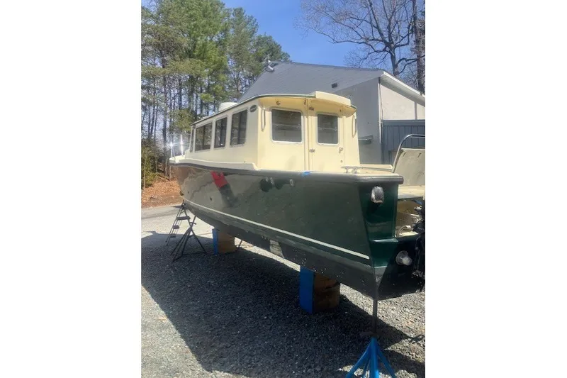 Slide: The Image of 2007 Caledon 27 Trailerable Pocket Trawler on stands, surrounded by trees and a building. - 22