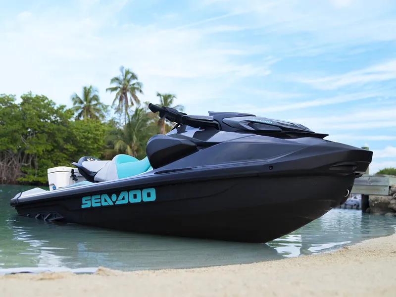 The Image of A Sea-Doo GTR 230 jet ski rests on the beach. It features a sleek design, black with turquoise accents. - 9
