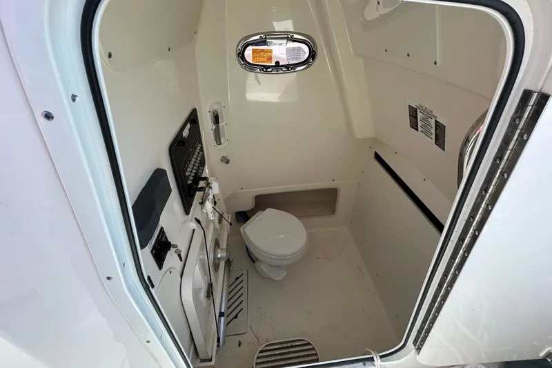 Slide: The Image of Interior of a 2020 Boston Whaler 280 Outrage boat bathroom with toilet and control panel. - 15