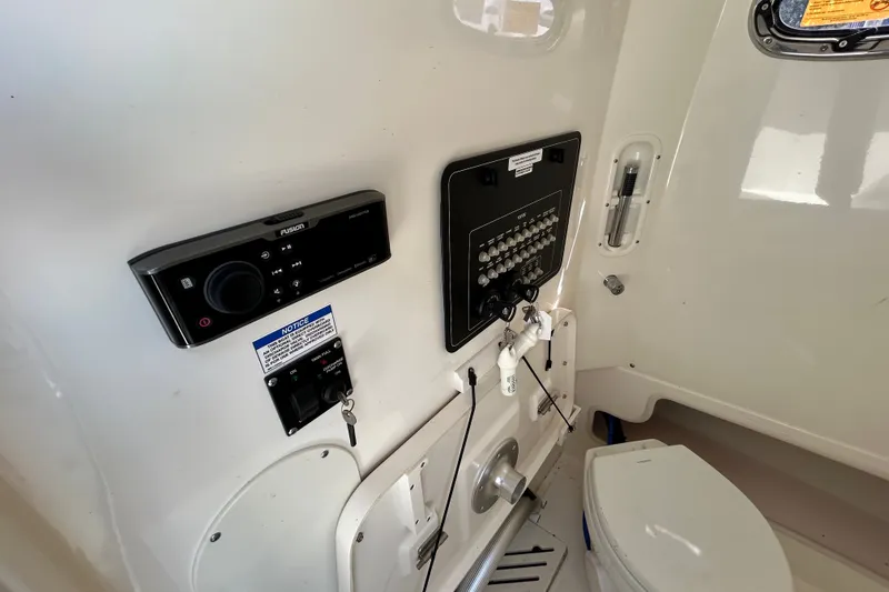 Slide: The Image of Interior of a 2020 Boston Whaler 280 Outrage boat, featuring control panel and marine toilet. - 17