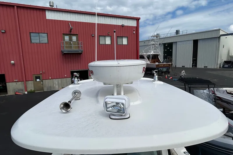 Slide: The Image of Boston Whaler 280 Outrage 2020 boat with radar and spotlight, docked near red building. - 14