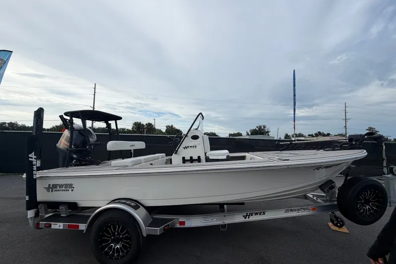 Slide: The Image of 2022 Hewes Redfisher 16 boat on trailer, side view, outdoors under cloudy sky. - 1