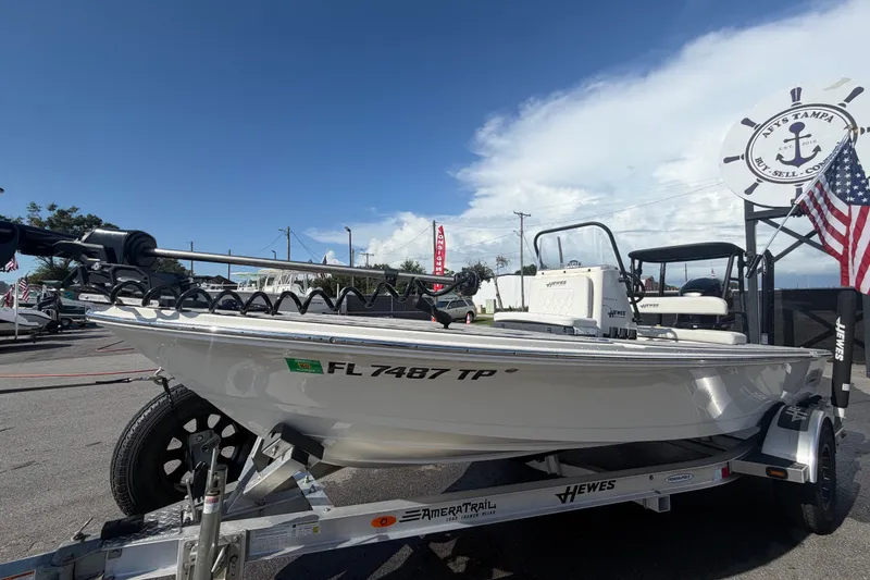 Slide: The Image of 2022 Hewes Redfisher 16 boat on trailer, displayed outdoors with American flag. - 9