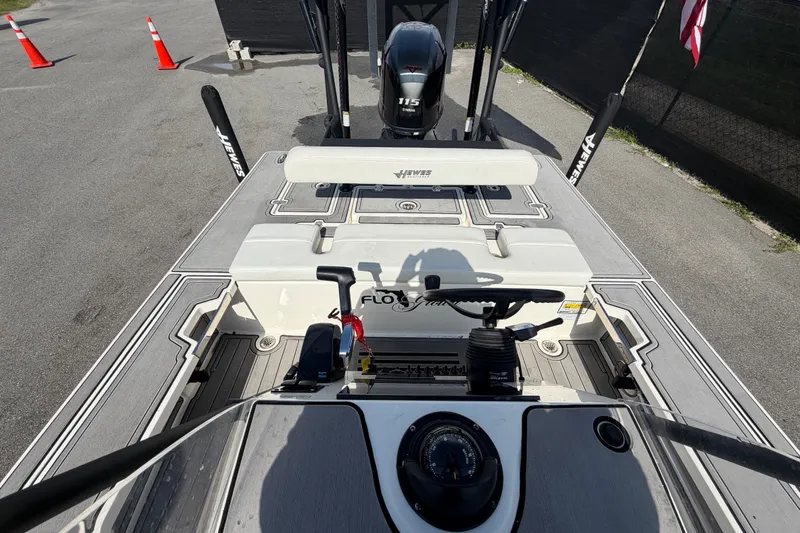 Slide: The Image of 2022 Hewes Redfisher 16 boat interior with steering wheel and motor, parked on pavement. - 42