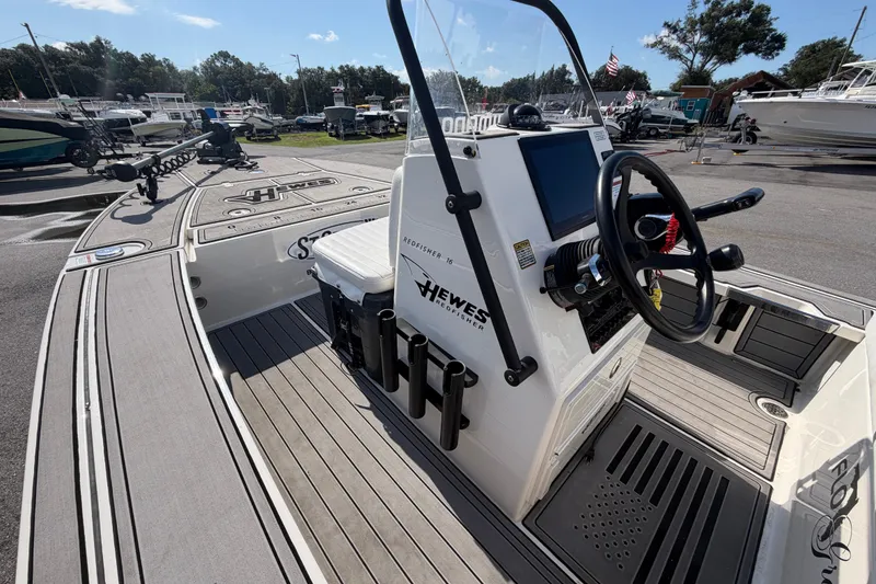 Slide: The Image of 2022 Hewes Redfisher 16 boat interior with steering console and seating at a marina. - 27