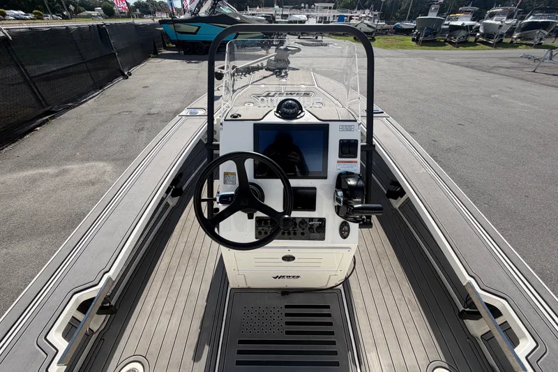 Slide: The Image of 2022 Hewes Redfisher 16 boat console with steering wheel and controls, docked outdoors. - 17