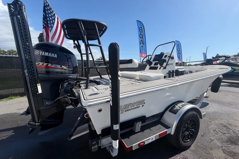 Slide: The Image of 2022 Hewes Redfisher 16 boat with Yamaha engine, displayed outdoors with flags. - 2