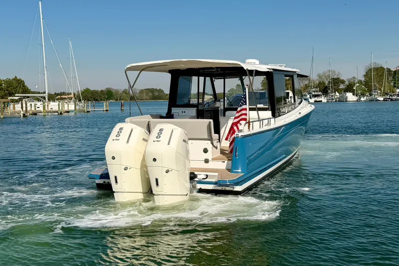 Slide: The Image of 2025 MJM 4 boat with twin outboard engines on a serene waterway. - 5