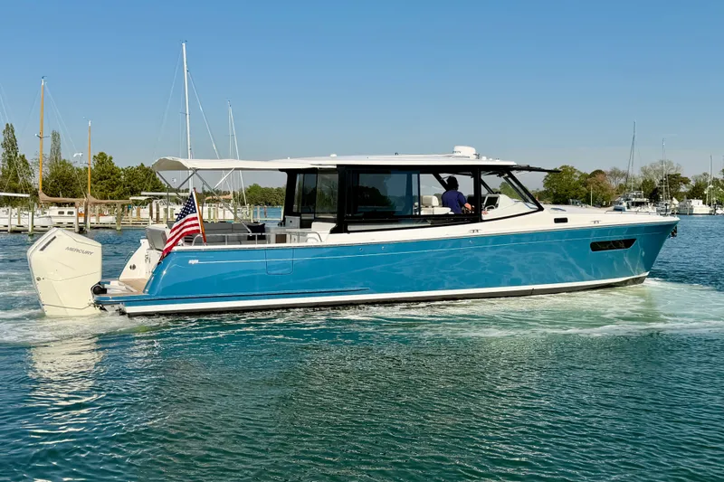 Slide: The Image of 2025 MJM 4 boat cruising on a sunny day with American flag displayed. - 3