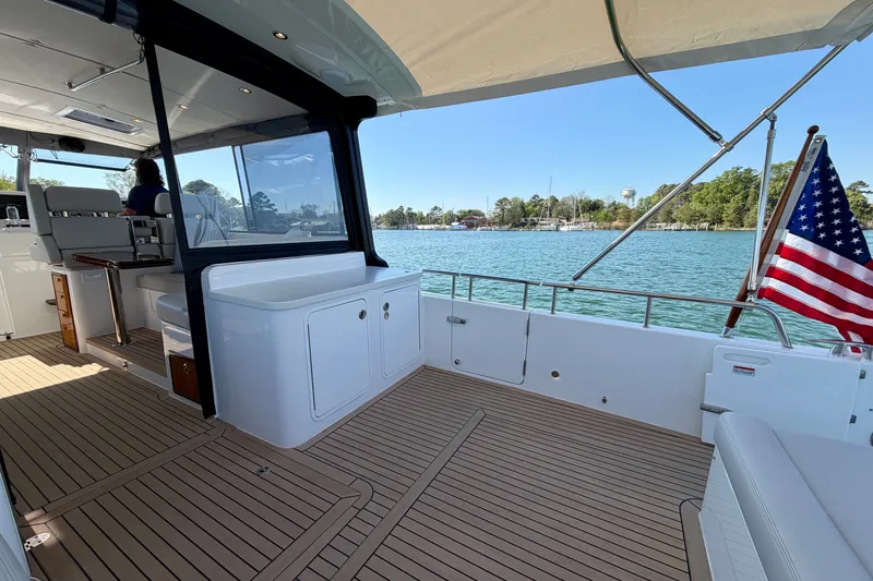 Slide: The Image of Luxury MJM 4 yacht deck, 2025 model, with American flag and scenic water view. - 17