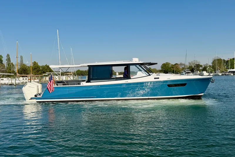 Slide: The Image of 2025 MJM 4 boat cruising on a sunny day, displaying sleek design and vibrant blue color. - 2
