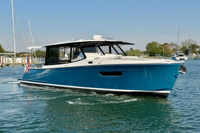 Slide: The Image of 2025 MJM 4 boat cruising on a calm waterway under a clear blue sky. - 1