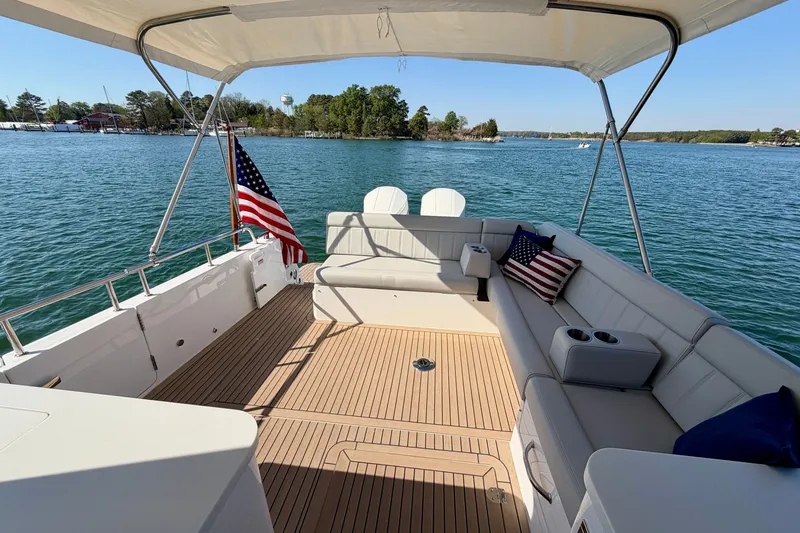 Slide: The Image of 2025 MJM 4 boat interior with seating, American flag, and scenic water view. - 18