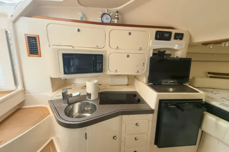 Slide: The Image of 2006 Grady-White Express 330 boat interior with kitchenette, microwave, sink, and TV. - 20