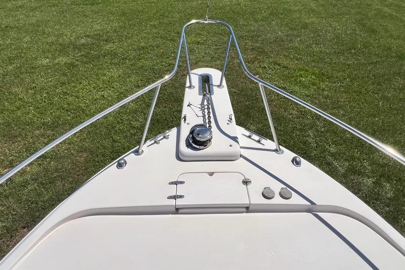 Slide: The Image of Bow of 2006 Grady-White Express 330 boat on grass, featuring anchor and railings. - 44