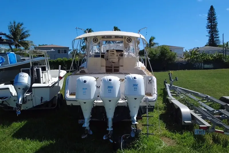 Slide: The Image of 2006 Grady-White Express 330 boat with triple outboard engines, parked on grass. - 3