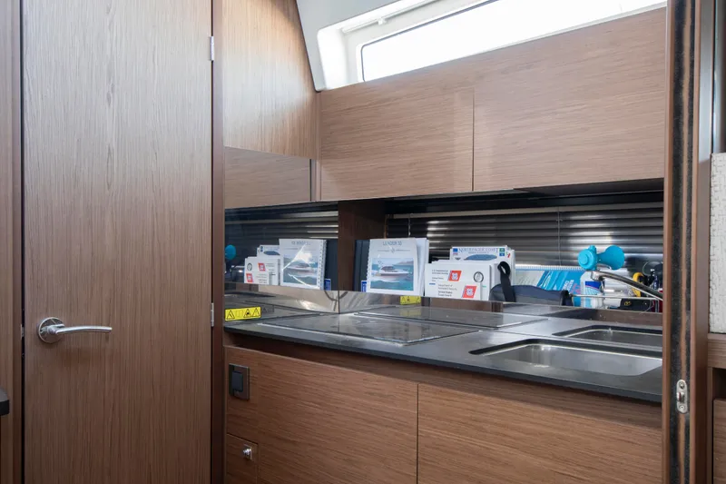Slide: The Image of The galley of a 2018 Jeanneau Leader 33 with wooden cabinets and a stainless steel sink. - 4