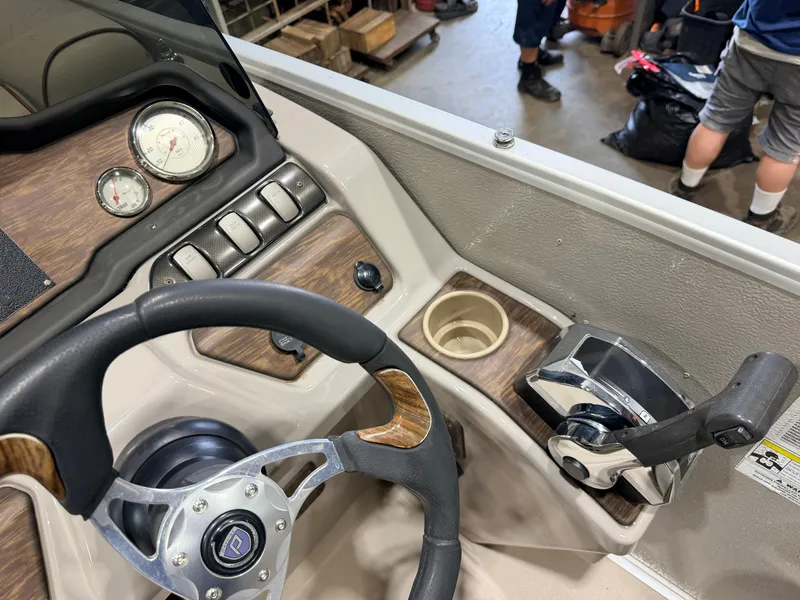 Slide: The Image of The image shows the helm of a Premier 221 Gemini Fish n Cruise boat with wood trim and throttle. - 19