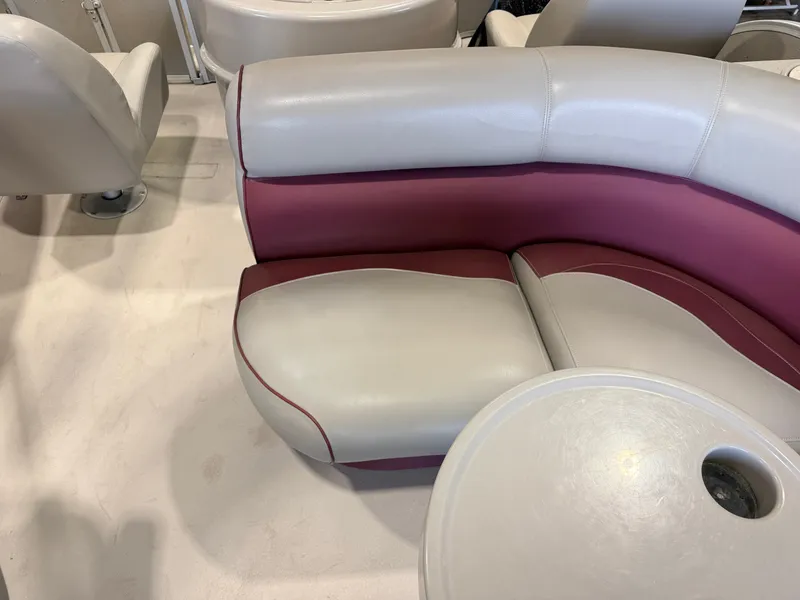 Slide: The Image of The interior of a boat with cream and maroon upholstery and a round table. - 25