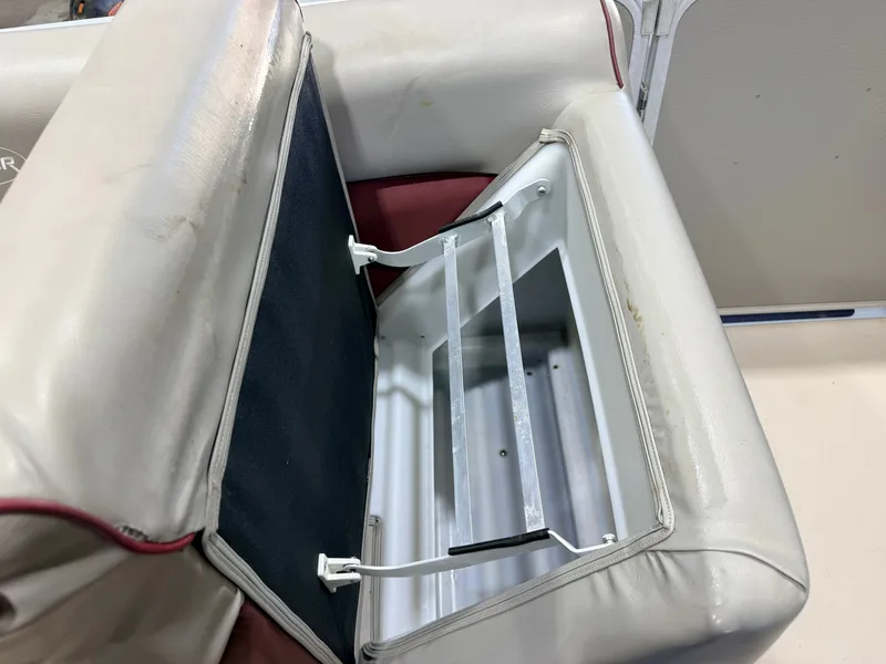 Slide: The Image of An open storage compartment in a boat seat with white upholstery and red accents. - 22