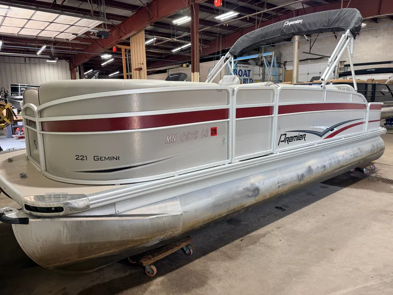 Slide: The Image of A silver Premier pontoon boat, model 221 Gemini, is situated in a warehouse. - 47