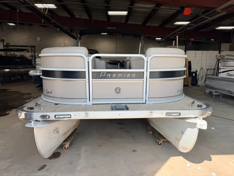Slide: The Image of A 2007 Premier 210 Legend pontoon boat is in a warehouse. It features two pontoons and a gray railing. - 35