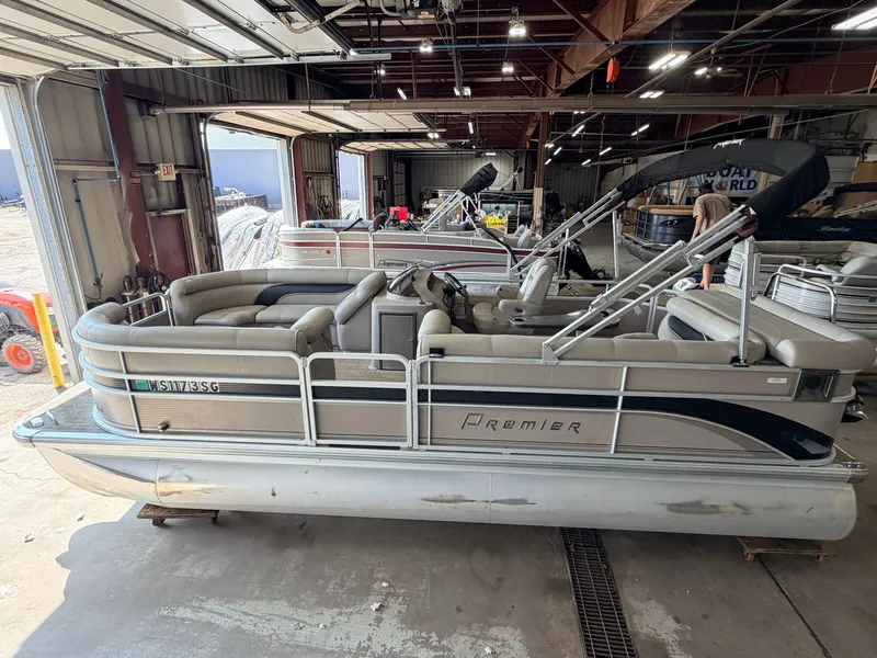 Slide: The Image of A 2007 Premier 210 Legend pontoon boat is in a warehouse. It features beige upholstery and a Bimini top. - 3