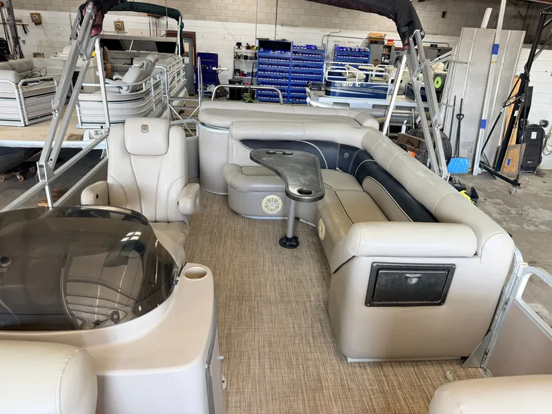 Slide: The Image of The image shows the interior of a 2007 Premier 210 Legend pontoon boat with beige seating and a table. - 4