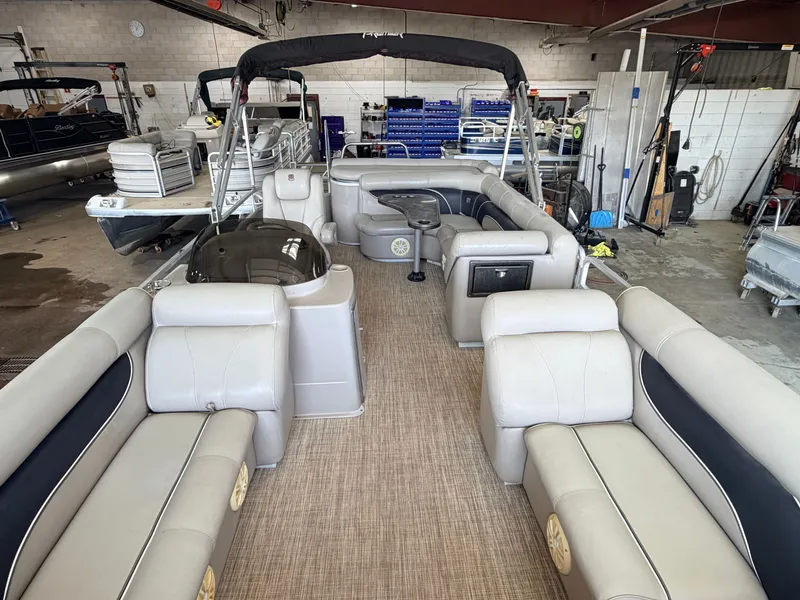 Slide: The Image of The image shows the interior of a 2007 Premier 210 Legend pontoon boat. It features beige upholstery and carpet flooring. - 2