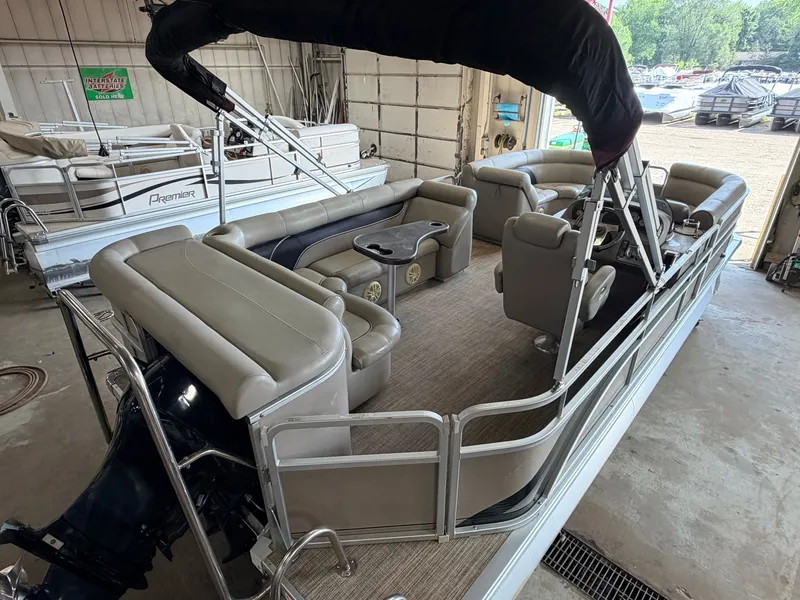 Slide: The Image of A 2007 Premier 210 Legend pontoon boat with beige seating and a black canopy in a warehouse. - 6