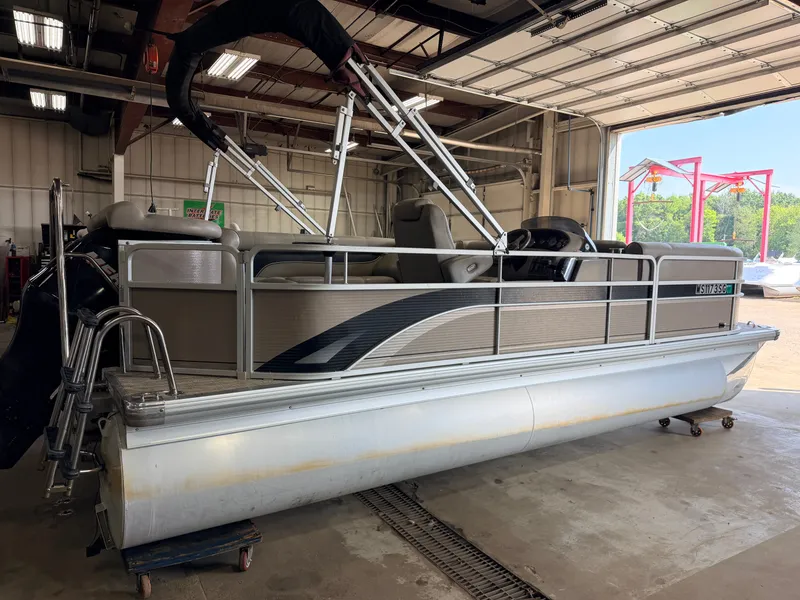 Slide: The Image of A 2007 Premier 210 Legend pontoon boat in a garage. It features an open deck and railing. - 43