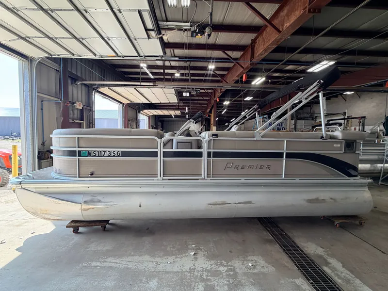 Slide: The Image of A 2007 Premier 210 Legend pontoon boat is in a warehouse. It features a simple design. - 26