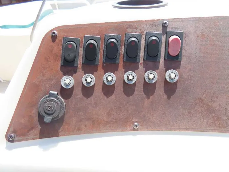 Slide: The Image of Control panel of a 1999 Bennington Pontoon with multiple switches and a 12V outlet. - 14