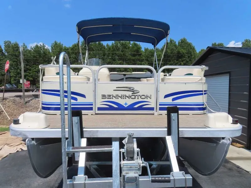 Slide: The Image of A 1999 Bennington Pontoon boat with a blue canopy and seating area, on a trailer. - 23