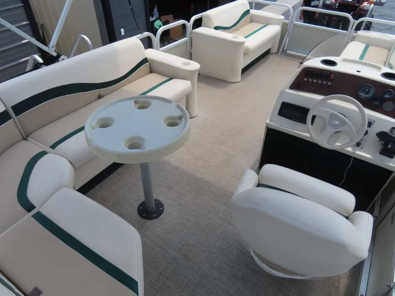 Slide: The Image of Interior of a 1999 Bennington Pontoon boat with beige seating and a table with cup holders. - 22