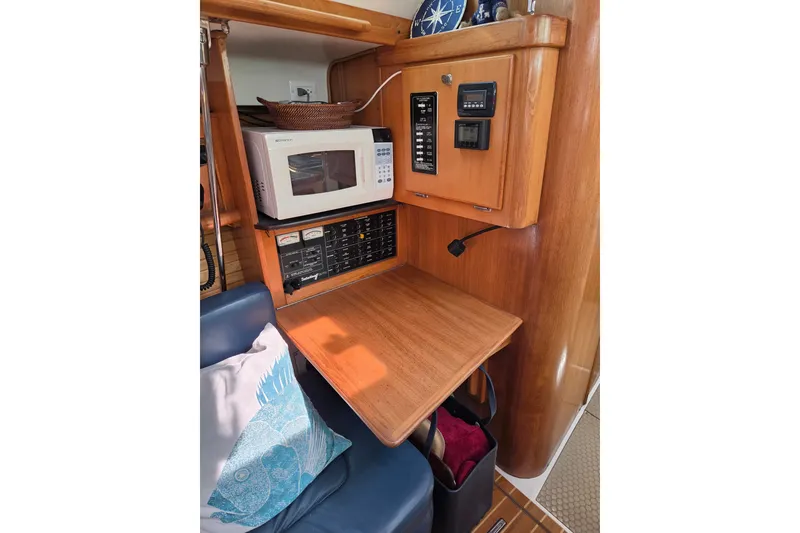 Slide: The Image of 2002 Catalina 390 yacht interior with microwave, control panel, and wooden table. - 34