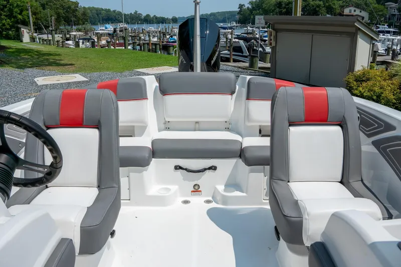 Slide: The Image of 2024 Tahoe T21 boat interior with red and gray seating, docked at a marina. - 13