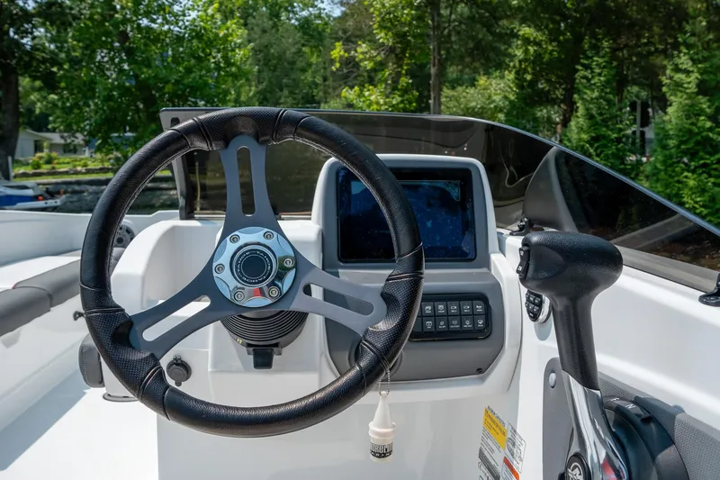 Slide: The Image of 2024 Tahoe T21 boat dashboard with steering wheel and control panel in a scenic setting. - 7